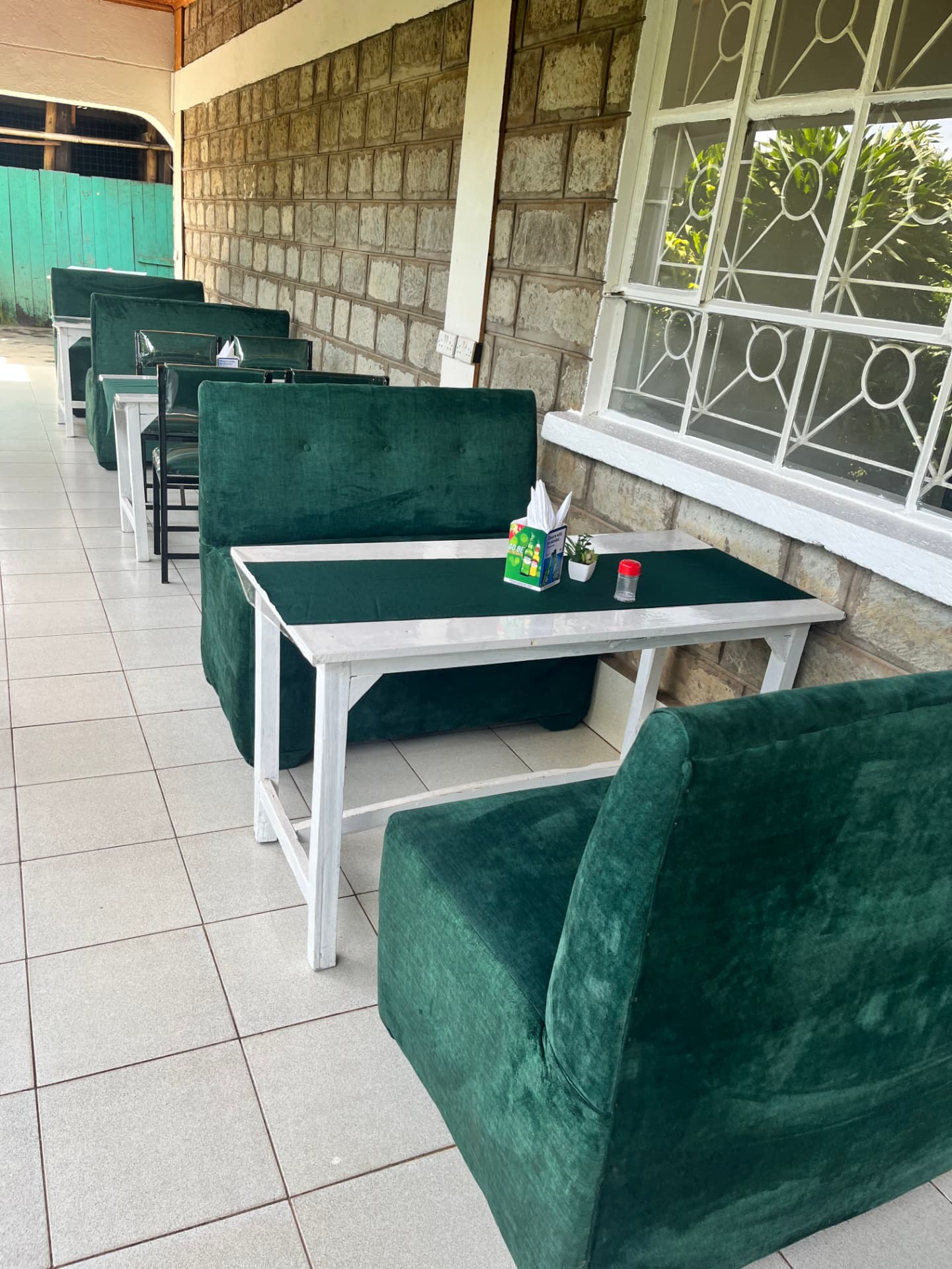 Veranda seating with green couches along the stone wall